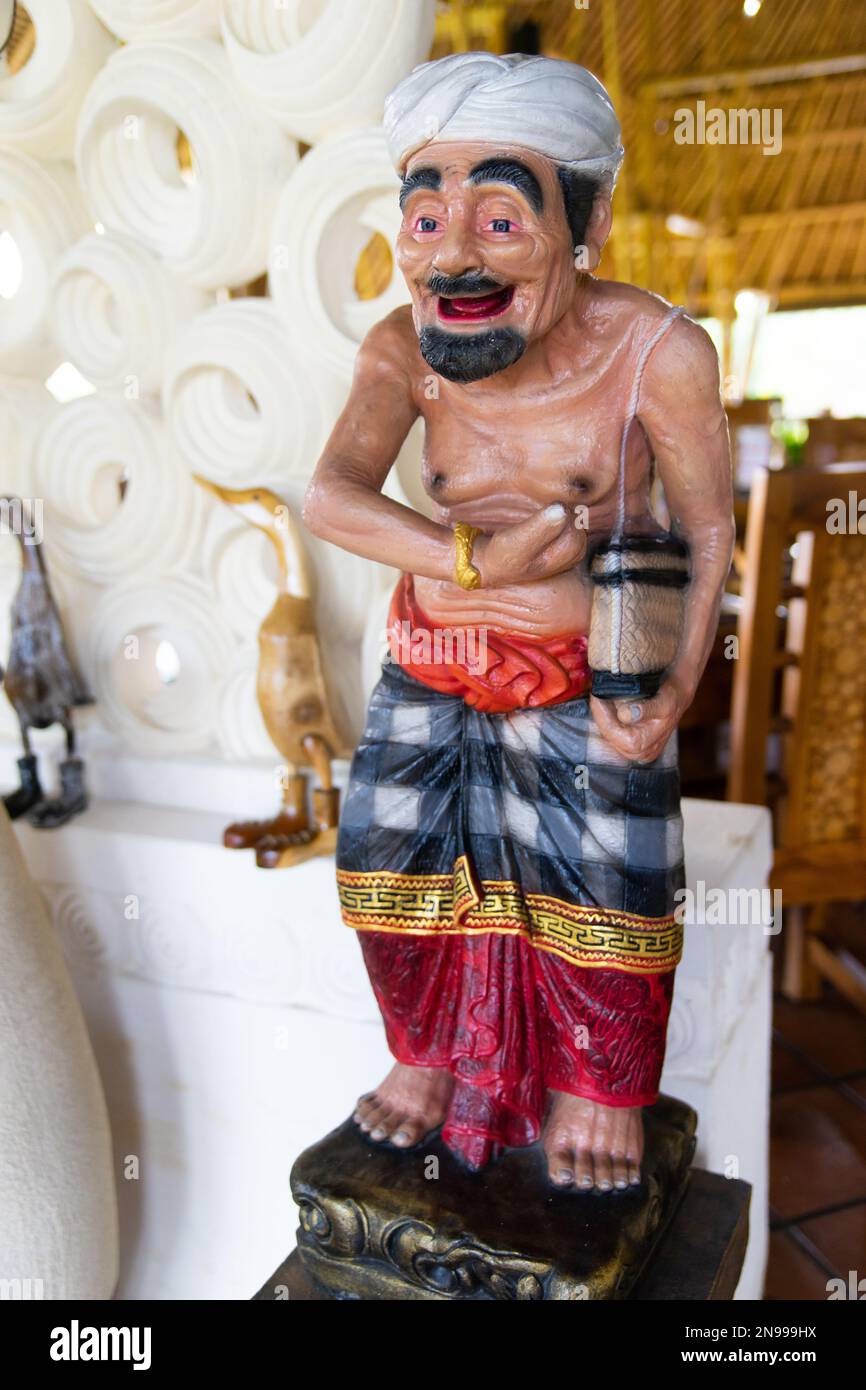 Una statua di scultura tradizionale di un vestito balinese maschile in sarung che accoglie i visitatori all'entrata di un ristorante Foto Stock