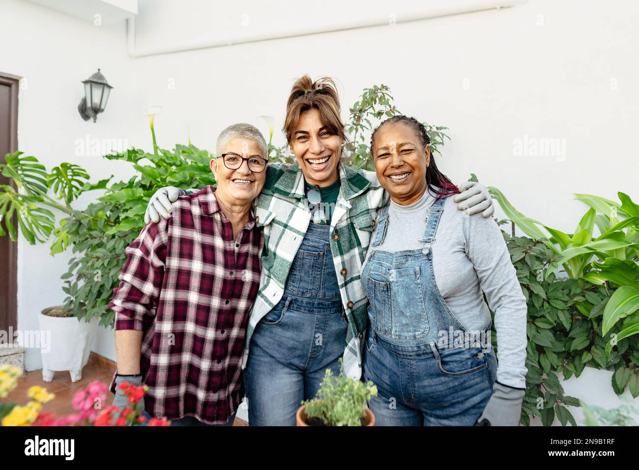 Donne multirazziali felici che fanno giardinaggio insieme a casa Foto Stock