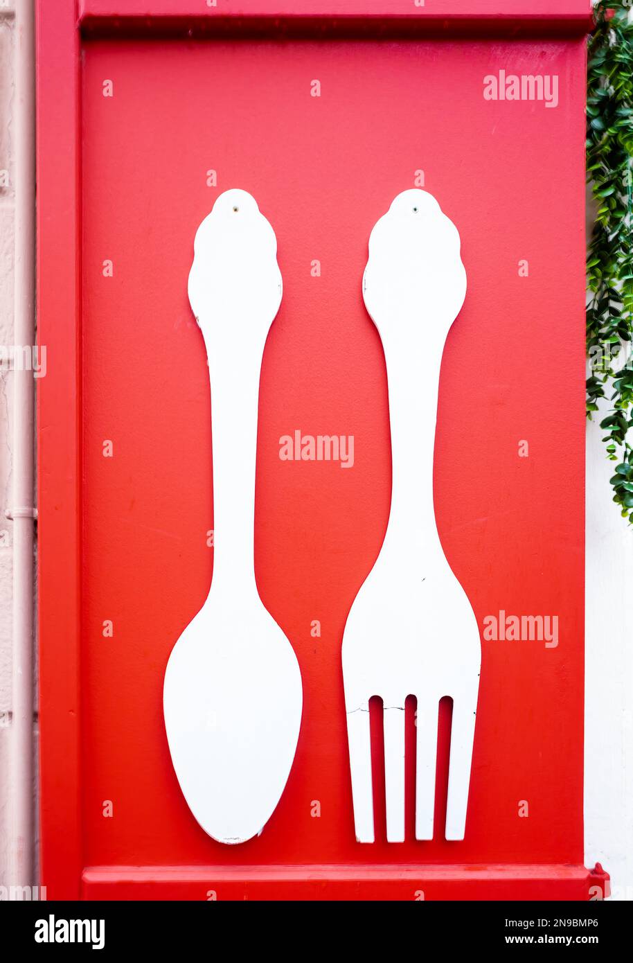 Forchetta e cucchiaio decorativi sulla serranda rossa di un ristorante a Colmar Foto Stock