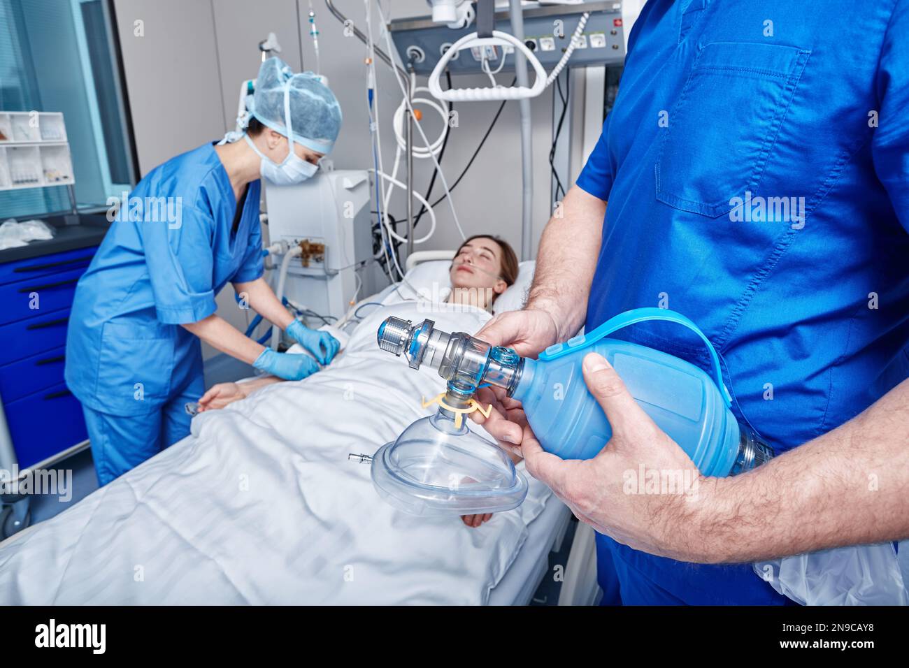 Medico che tiene la maschera per l'ossigeno vicino a un paziente incosciente in terapia intensiva durante la rianimazione cardiopolmonare. Unità di terapia intensiva Foto Stock
