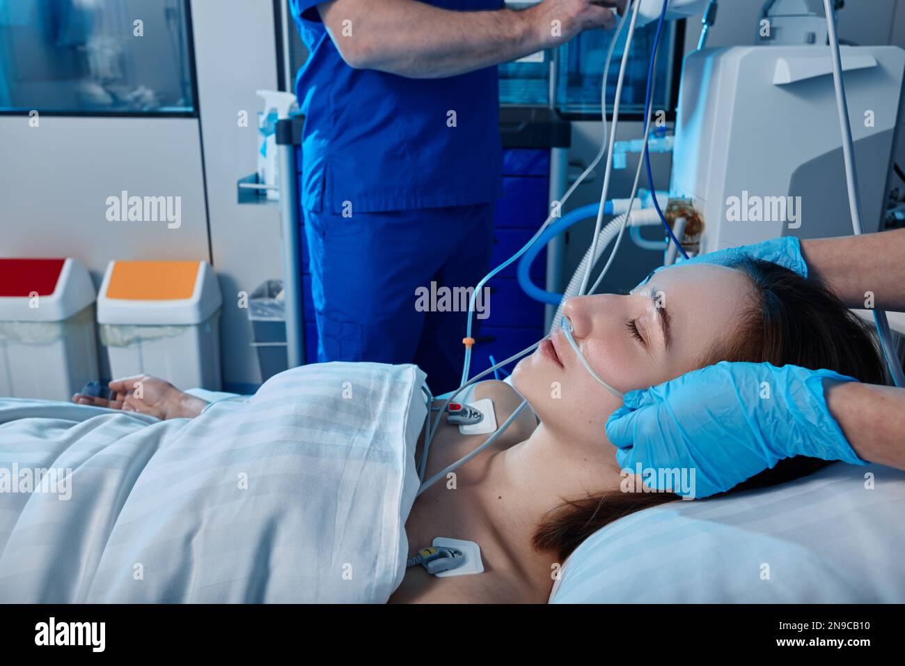 ICU. Personale infermieri che si occupano di pazienti di sesso femminile con cannula nasale per ossigeno nell'unità di terapia intensiva Foto Stock