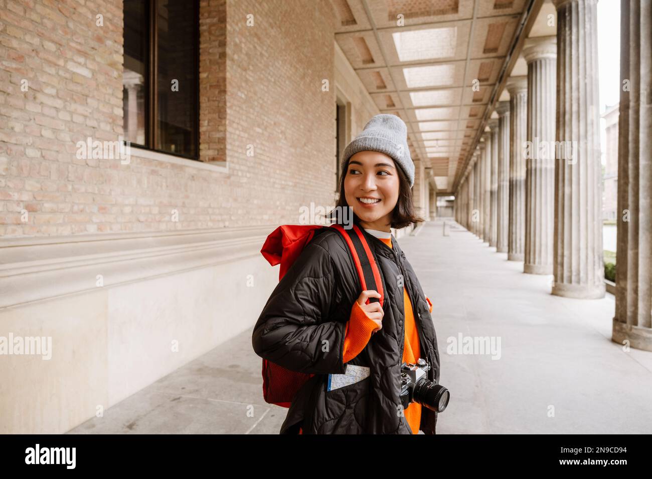 Bella giovane ragazza asiatica sorridente turista con zaino e macchina fotografica a piedi attraverso la strada della città vecchia Foto Stock