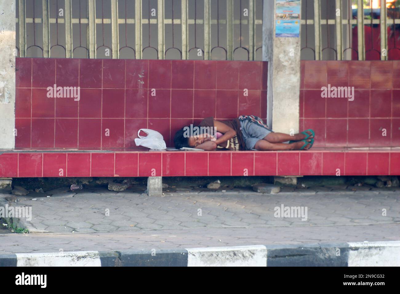 foto candida di una persona senza casa che dorme ad una fermata dell'autobus Foto Stock