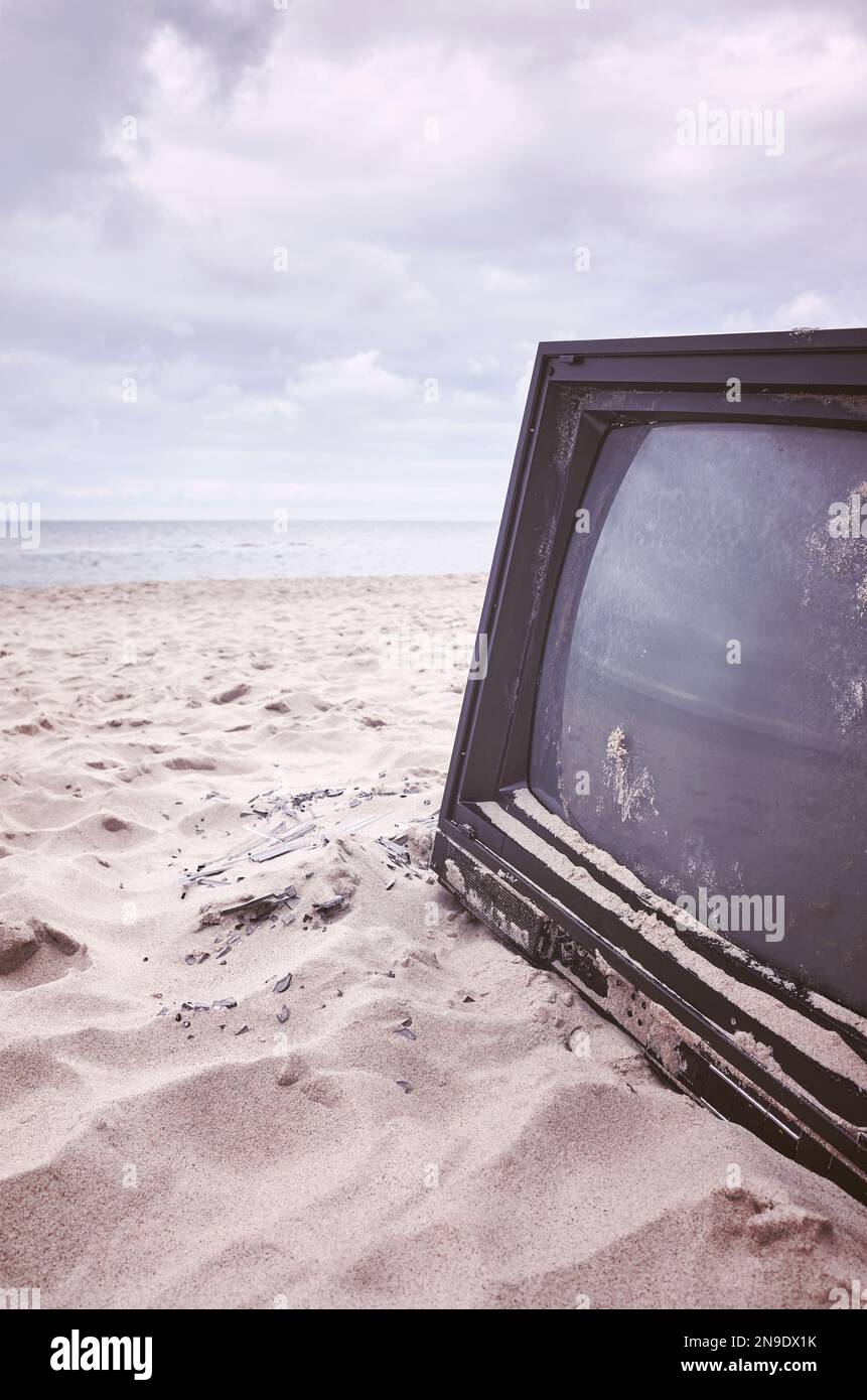 Vecchio televisore rotto su una spiaggia, tonalità di colore applicato. Foto Stock