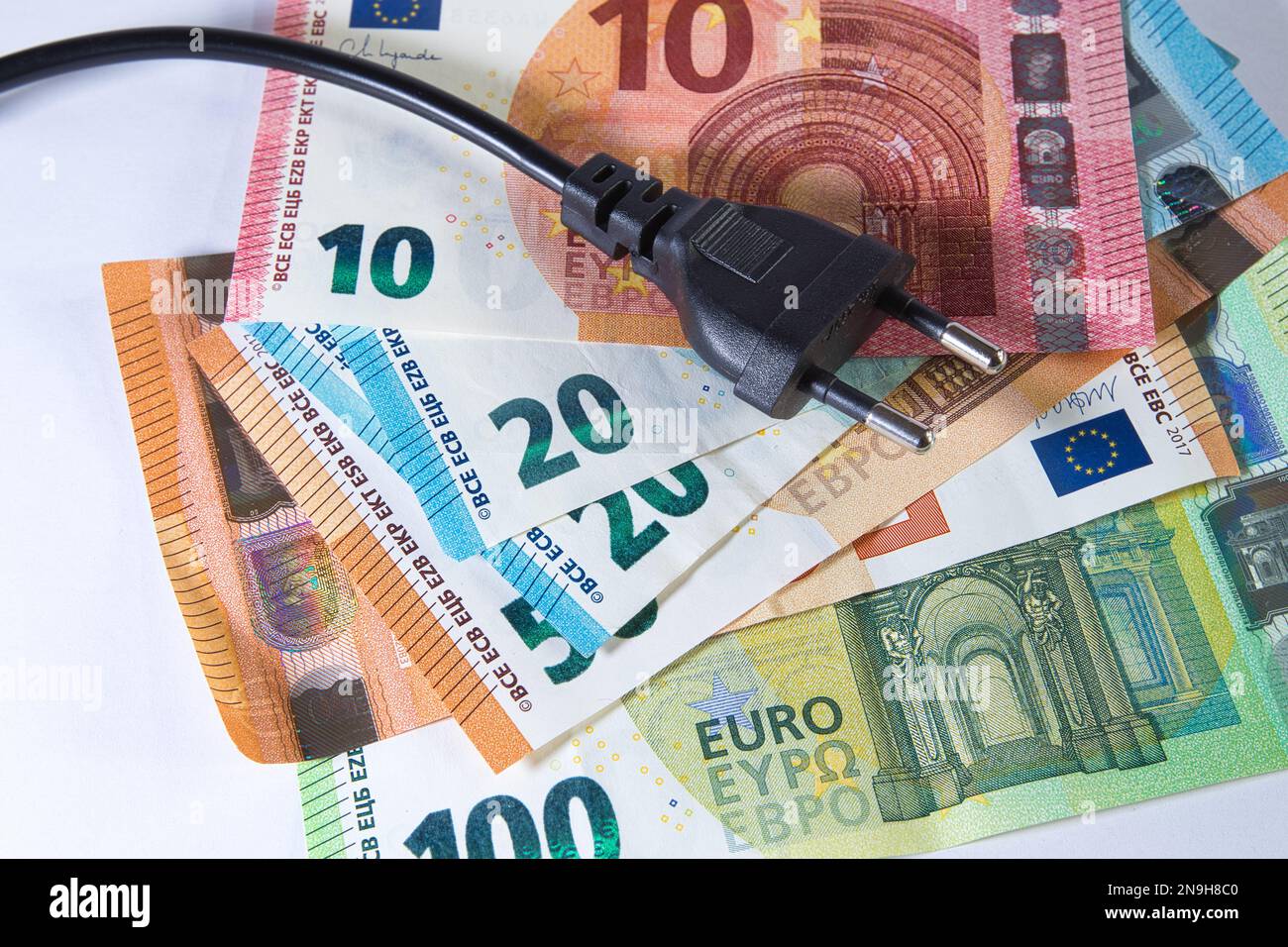 denaro europeo in un mucchio con connettore maschio che illustra l'aumento dei costi energetici Foto Stock