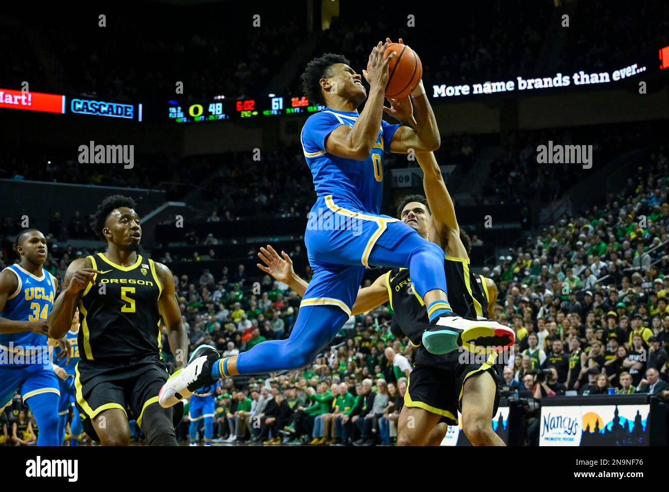 UCLA guard Jaylen Clark (0) drives to the basket as Oregon guard Will Richardson, right, tries to get a handoff the ball during the second half of an NCAA college basketball game Saturday, Feb. 11, 2023, in Eugene, Ore. (AP Photo/Andy Nelson) Foto Stock