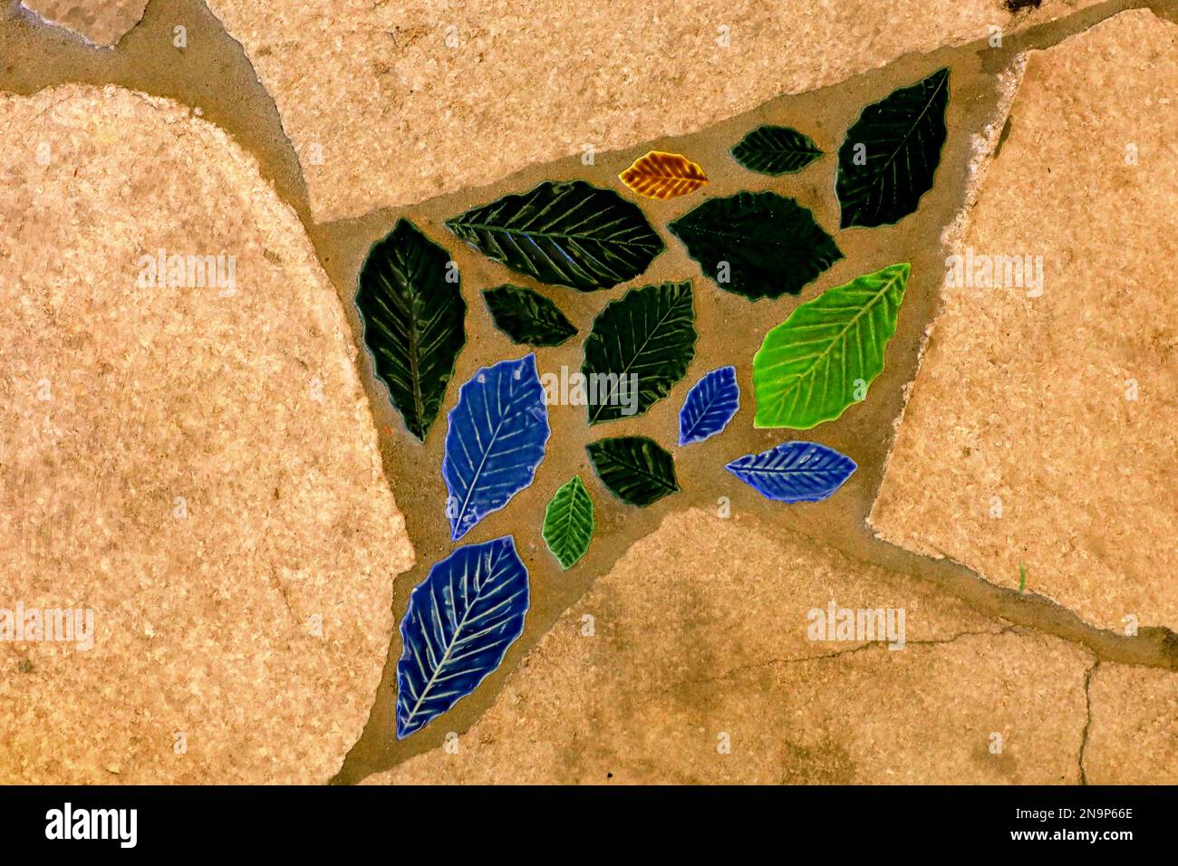 Foto piatta di una superficie stradale composta da arenaria gialla e piastrelle colorate a foglia Foto Stock