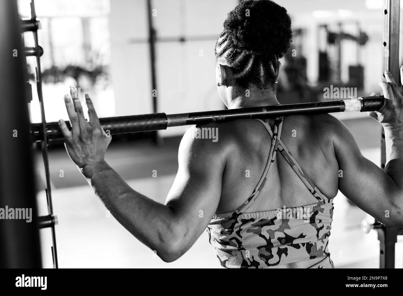 Donna determinata che fa esercizi di squat con un barbell e barbell in palestra. Rinforzo della carrozzeria. Foto Stock