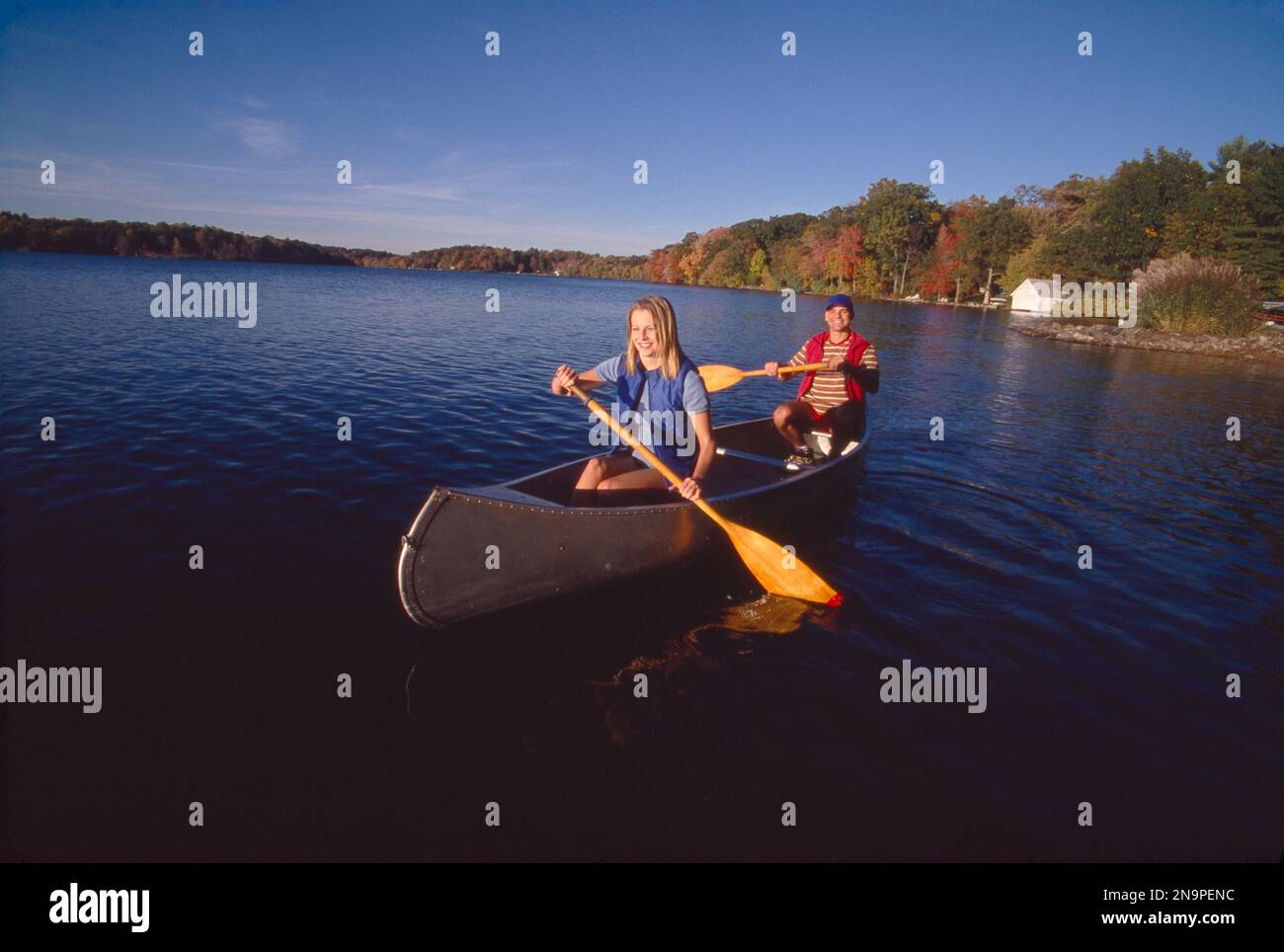 Coppia giovane fuori pagaiare in una canoa sul lago in autunno Foto Stock