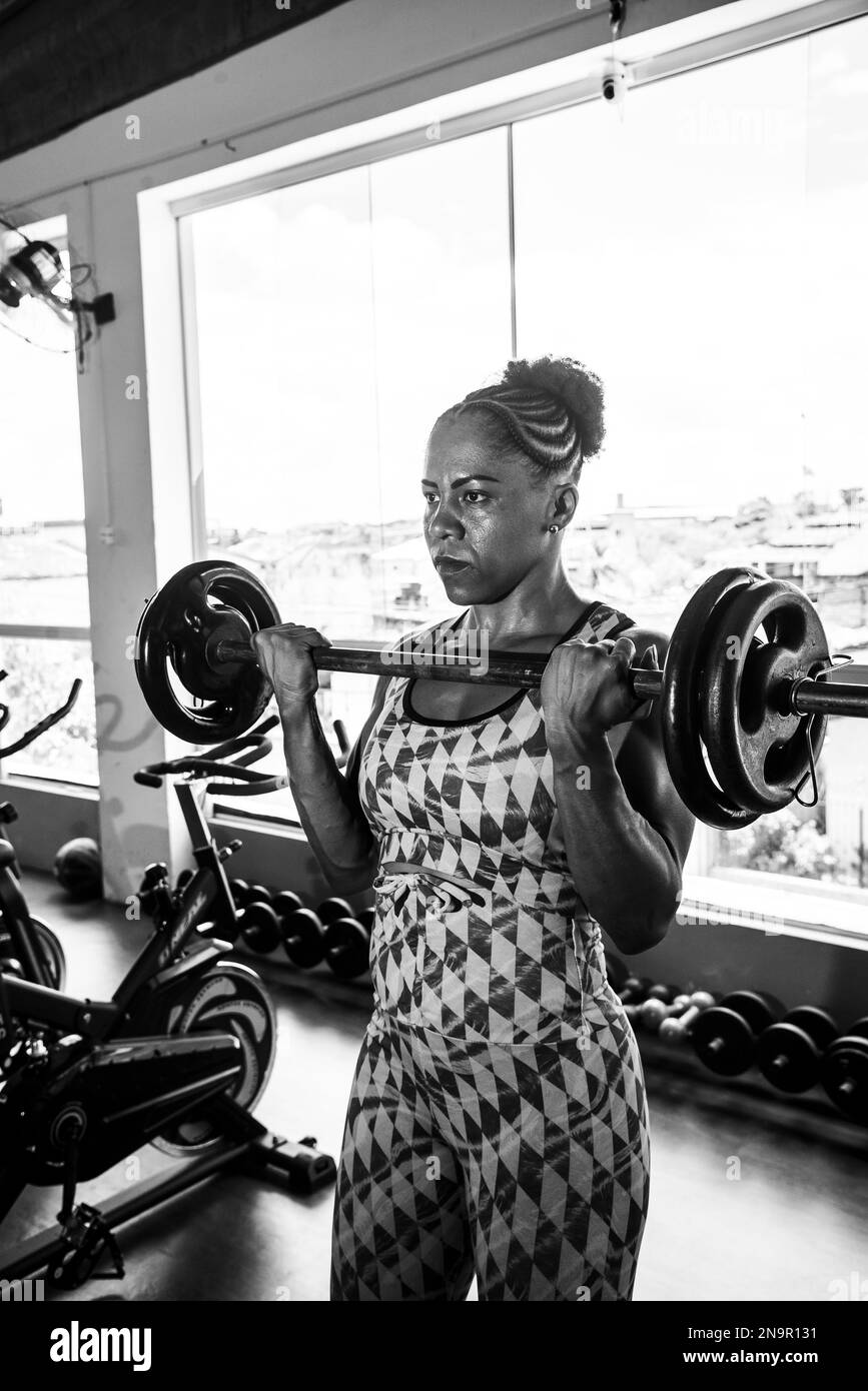 Donna determinata sollevamento pesi in palestra. Rafforzamento delle braccia. Foto Stock