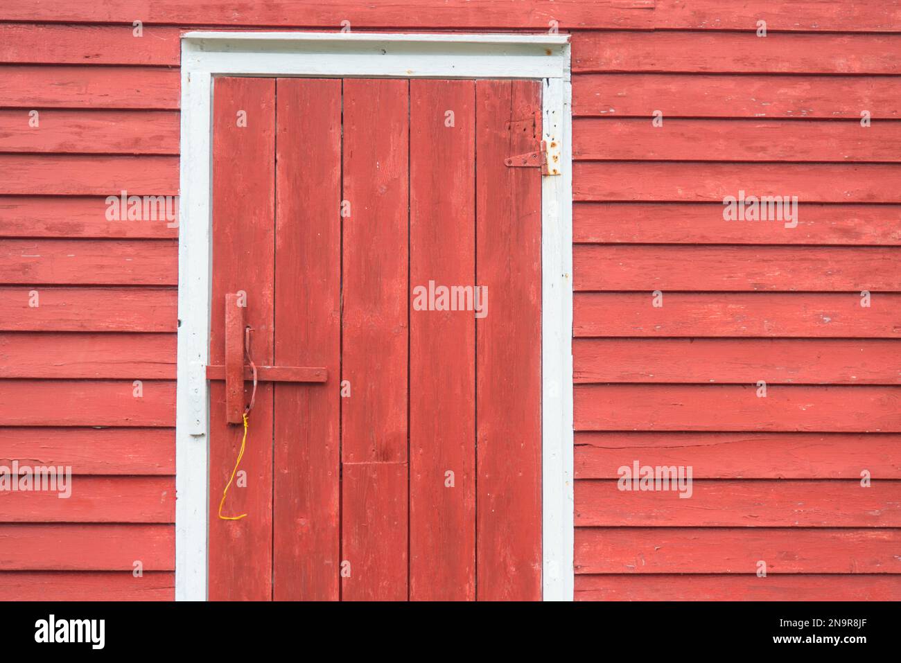Primo piano di una porta di legno in una pescheria rossa con lati di legno; Battle Harbour, Terranova e Labrador, Canada Foto Stock