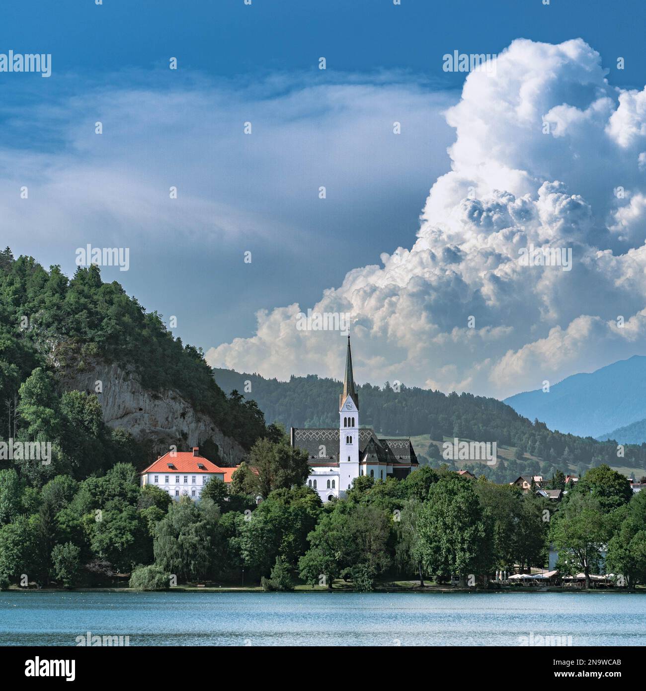Lago di Bled con una chiesa Zupnijska cerkev svetega Martina- Chiesa di San Martina, Bled, con uno sfondo di nuvole bianche in estate Foto Stock