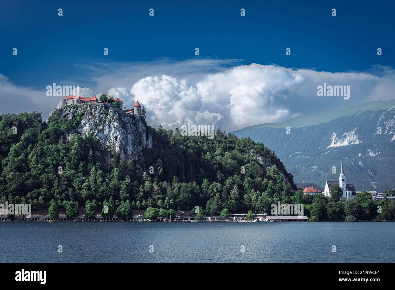 Lago di Bled con un castello di Bled in cima alla roccia e Chiesa di San Martina, Bled, con uno sfondo di nuvole bianche Foto Stock