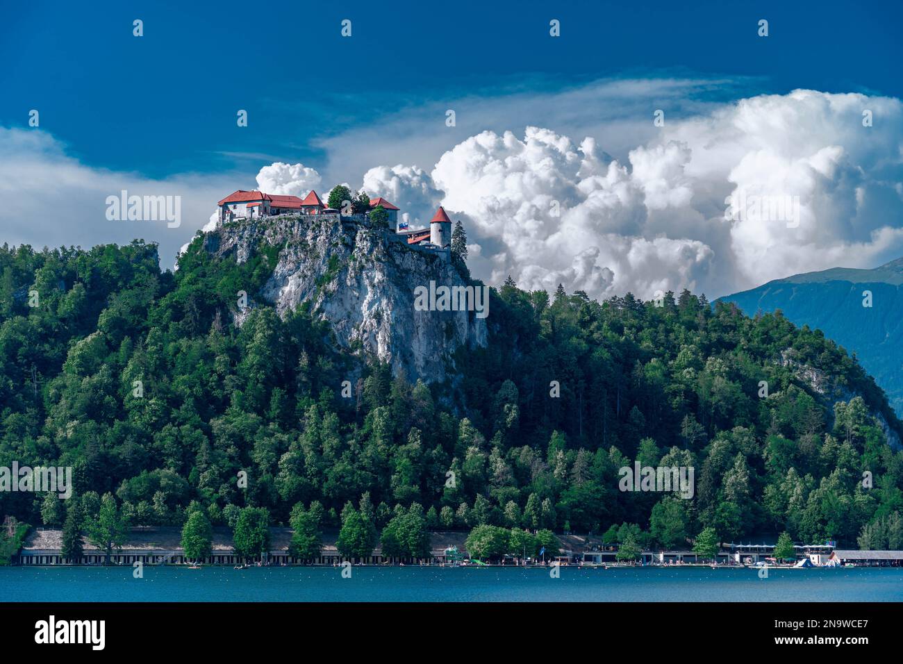 Lago di Bled con un castello di Bled in cima alla roccia, con uno sfondo di nuvole bianche in estate Foto Stock