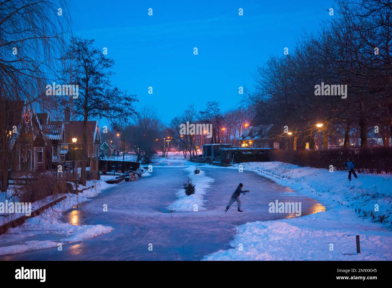 Pattinatore di ghiaccio da solo su un canale di notte; Amsterdam, Paesi Bassi Foto Stock