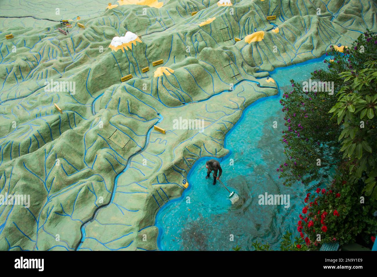 Il membro del personale scruba le alghe dal fondo della sezione oceanica di una gigantesca mappa di rilievo della Colombia a Parque Jaime Duque; Bogotà, Colombia Foto Stock