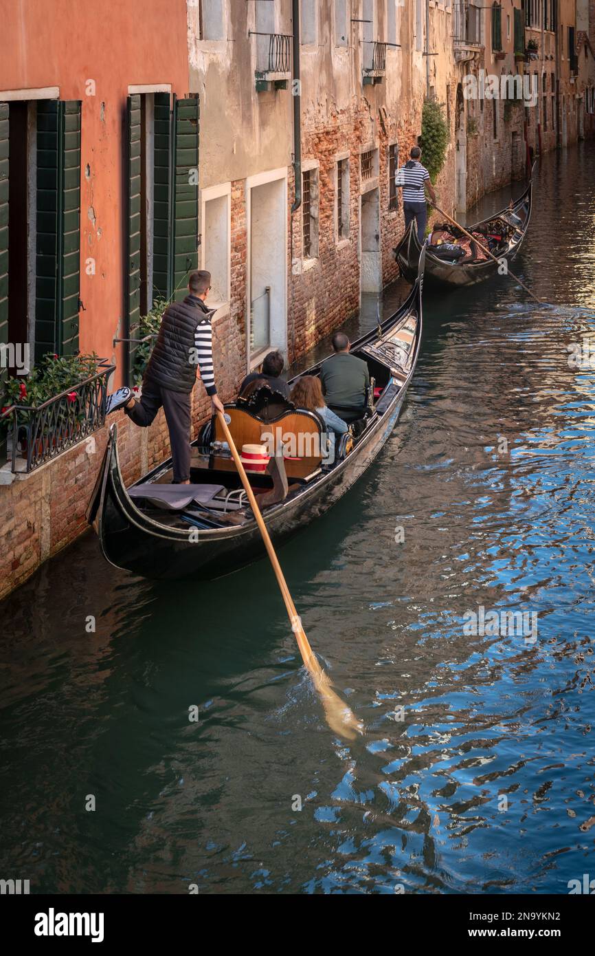 Il gondoliere spinge la gondola fuori dalle mura su un canale di Venezia Foto Stock