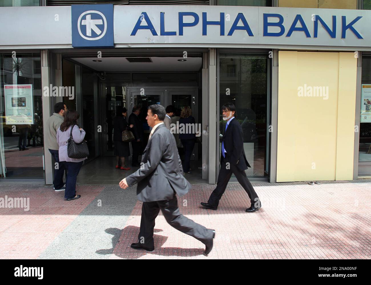 Pedestrians pass outside an Alpha Bank branch in Athens, Friday, April 20, 2012. Greek banks will publish their annual reportslater Friday, which are expected to include severe lossesresulting from their participation in the country's massive private debt writedown earlier this year. (AP Photo/Thanassis Stavrakis) Foto Stock