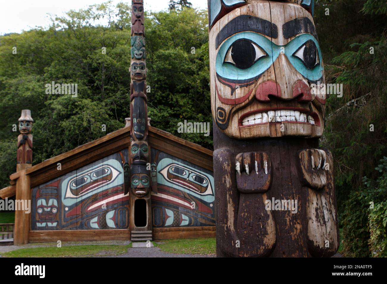 Pali totem e casa del clan presso il Totem Bight Historic Site; Ketchikan, Alaska, Stati Uniti d'America Foto Stock