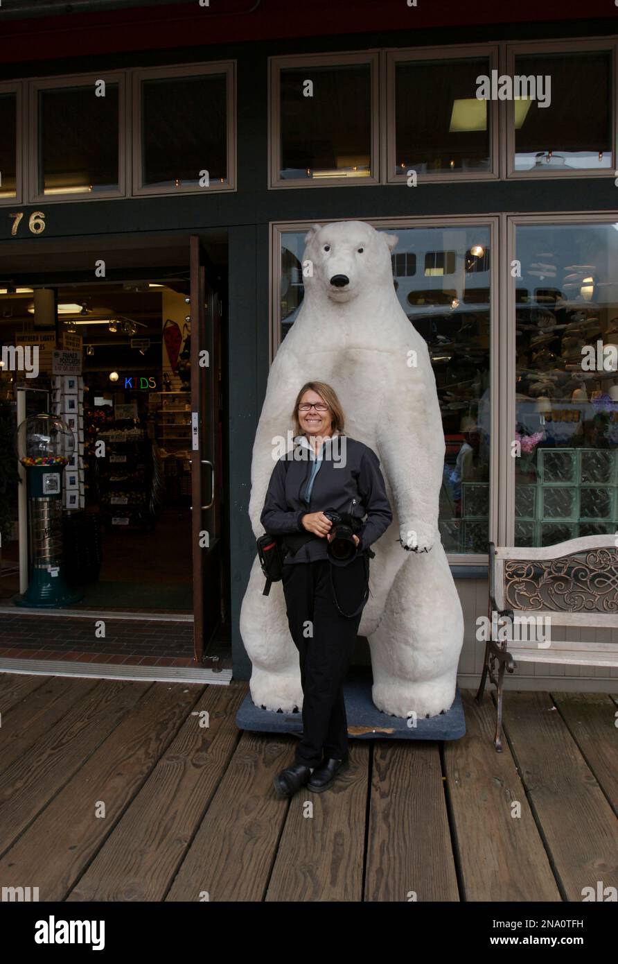 Fotografa donna posa con un orso polare imitato fuori da un negozio a Ketchikan, Alaska, Stati Uniti; Ketchikan, Alaska, Stati Uniti d'America Foto Stock