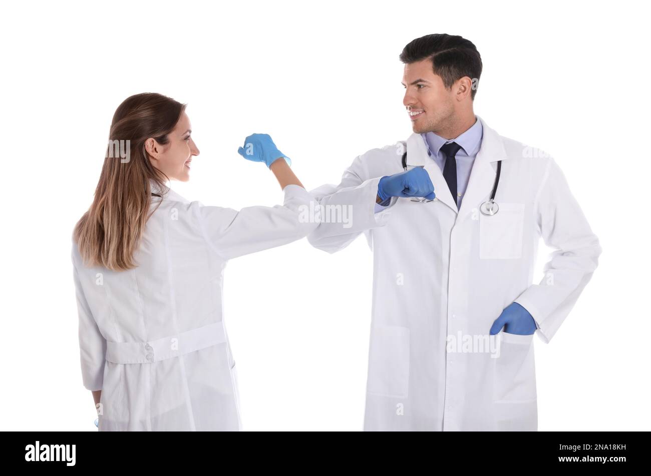 I medici si salutano a vicenda saltando i gomiti invece di fare una stretta di mano su sfondo bianco Foto Stock