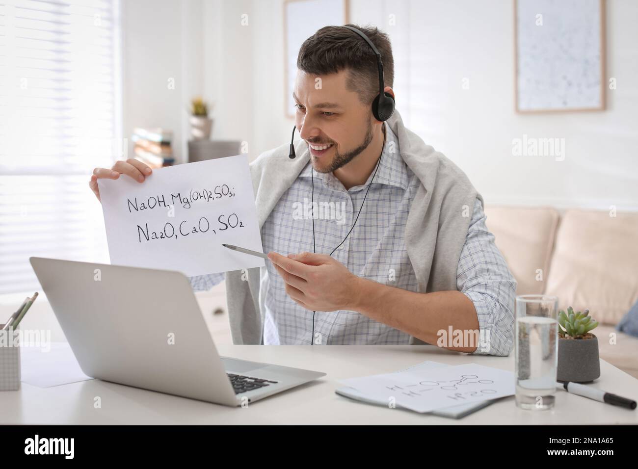 Insegnante che conduce una lezione online a casa durante la quarantena COVID-19 Foto Stock