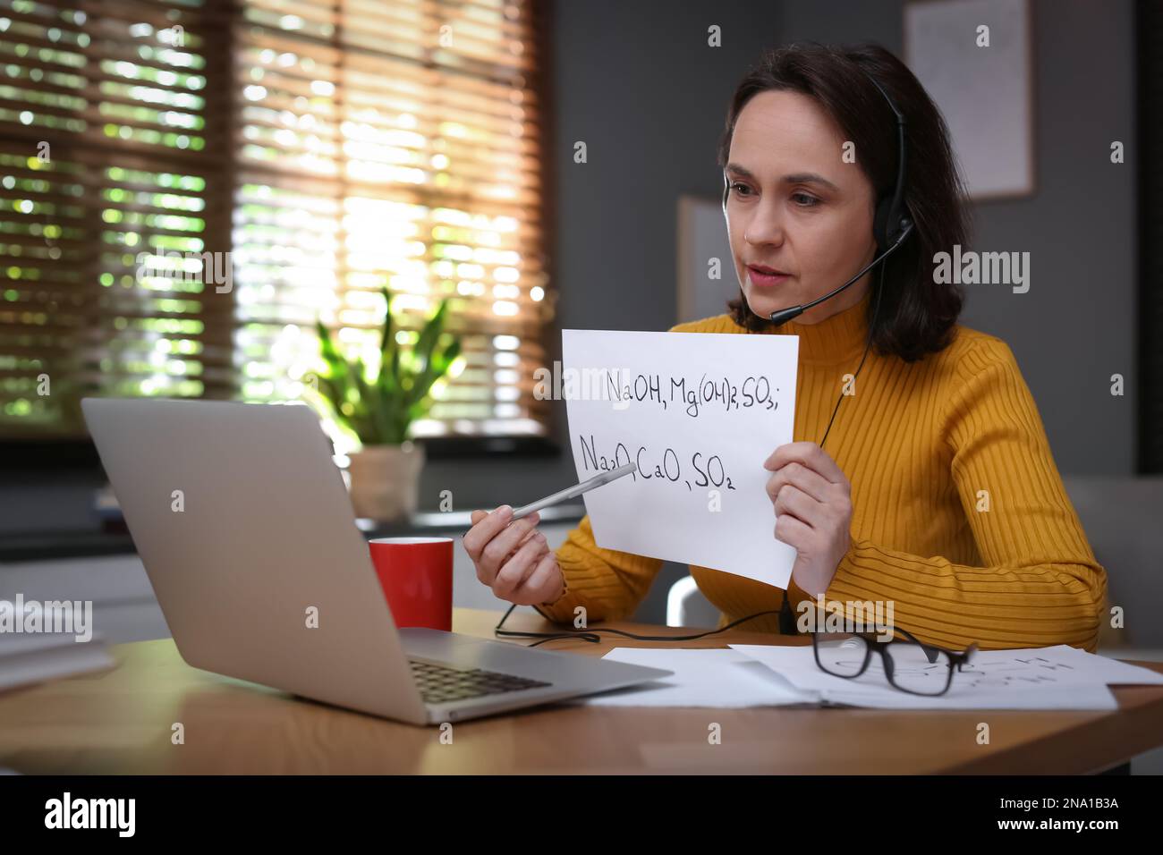 Insegnante che conduce una lezione online a casa durante la quarantena COVID-19 Foto Stock