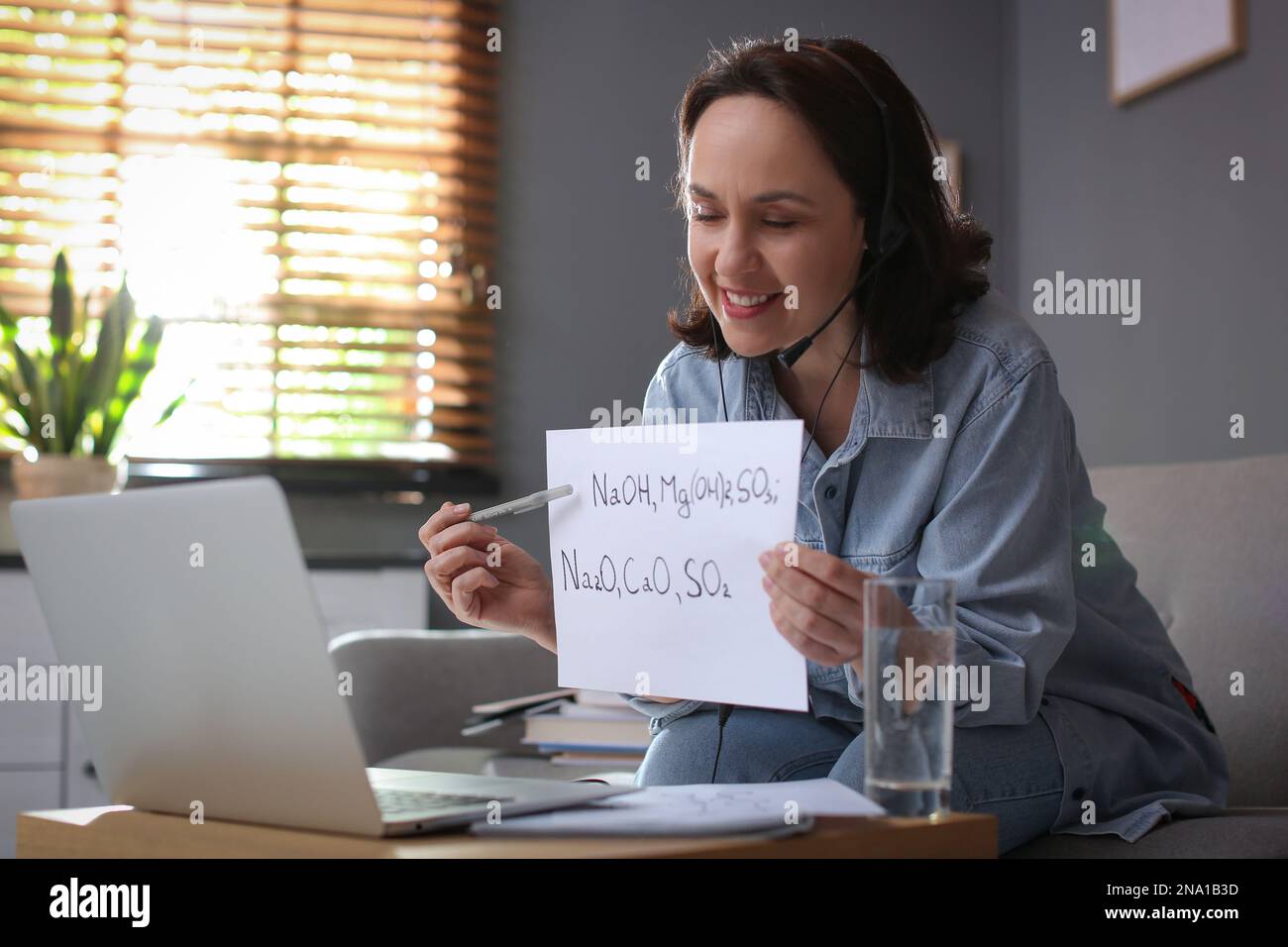 Insegnante che conduce una lezione online a casa durante la quarantena COVID-19 Foto Stock