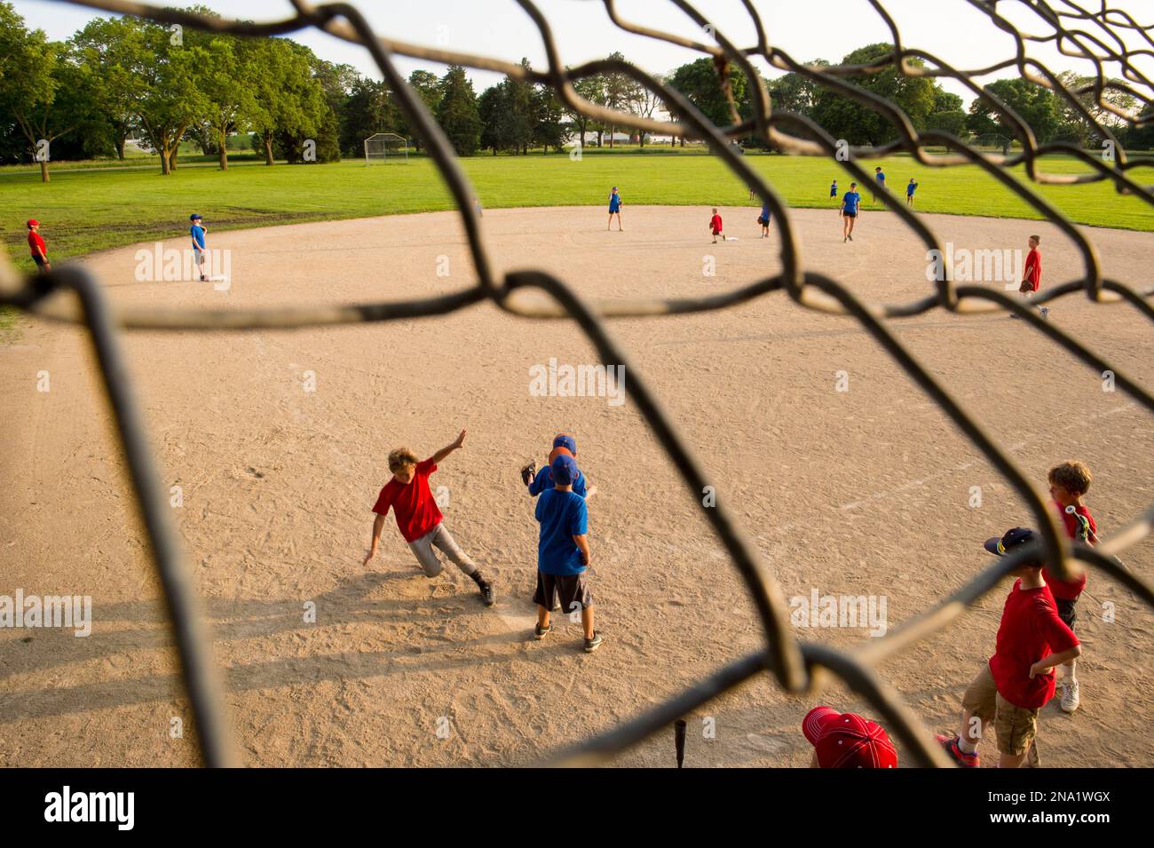 Ragazzo di età elementare torna a casa durante una partita di t-ball con i suoi compagni di squadra in piedi dietro e a guardare; Lincoln, Nebraska, Stati Uniti d'America Foto Stock