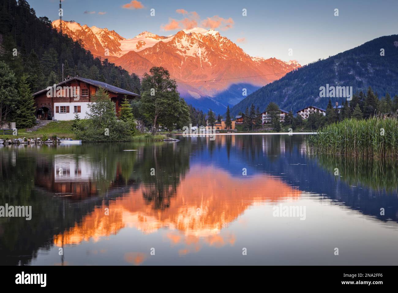 Bagliore di tramonto color pastello sulle montagne che si riflettono sul lago di Champex; Champex, Vallese, Svizzera Foto Stock