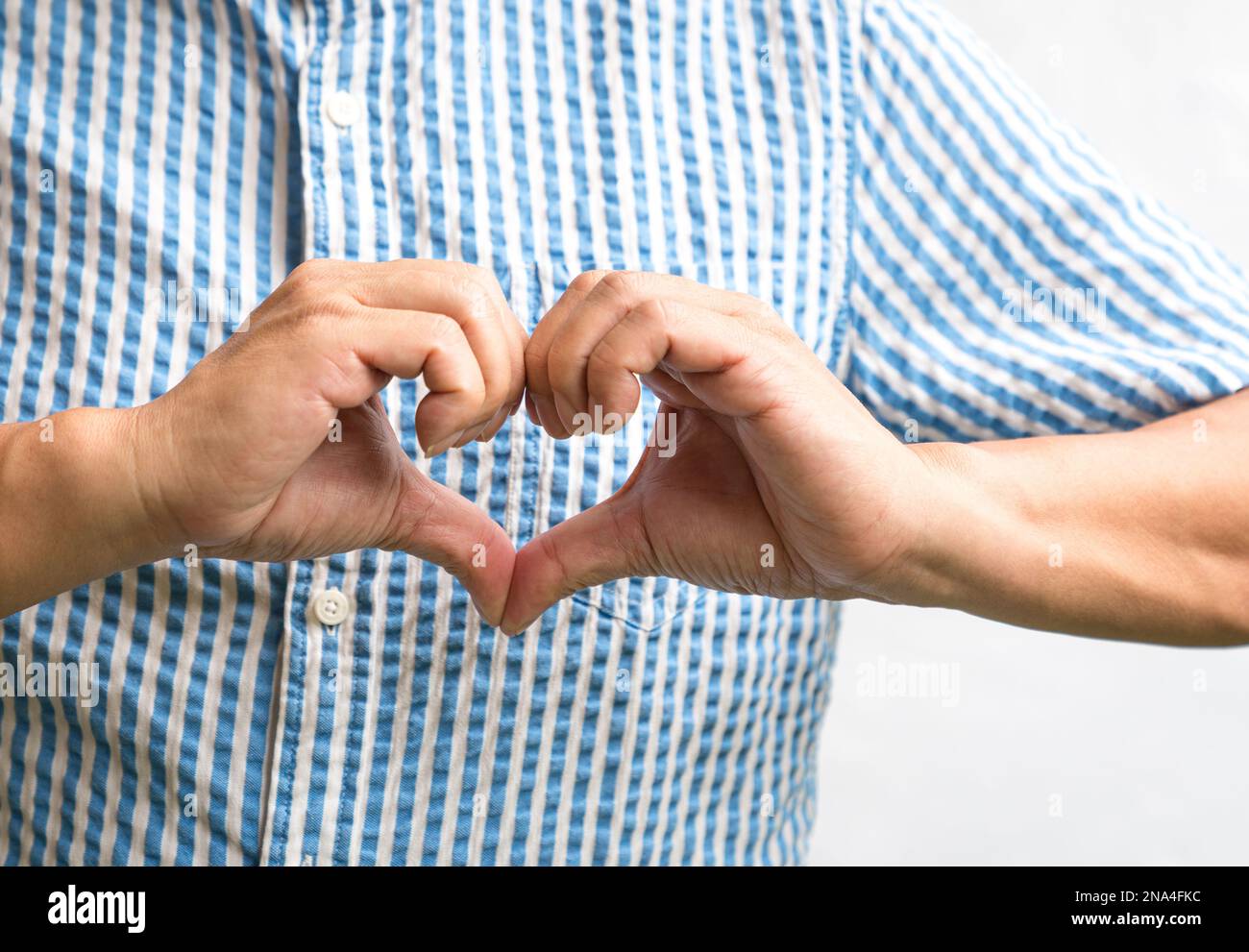 Uomo che mostra la forma del cuore fatto con le mani. Primo piano. Foto Stock