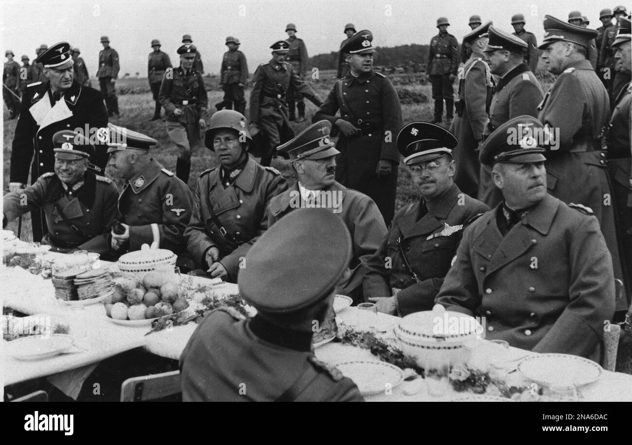 Adolf Hitler is surrounded by his aides, all of them high in the German Reich, during a field meal near Eger, Czechoslovakia, Oct. 3, 1938. The potatoes and pumpernickel bread in front of Der Fuehrer, a strict vegetarian, and the unbroken line of guards stationed out of hearing behind the table. From left, (first man unidentified) Heinrich Himmler, Gestapo chief; General W. Von Reichnau, commander of the Army Corps which occupied the Third Zone; Hitler; Konrad Heinlein, Czech Nazi leader; and Gen. Wilhelm Keitel, chief of the high command of the German Army. (AP Photo) Foto Stock