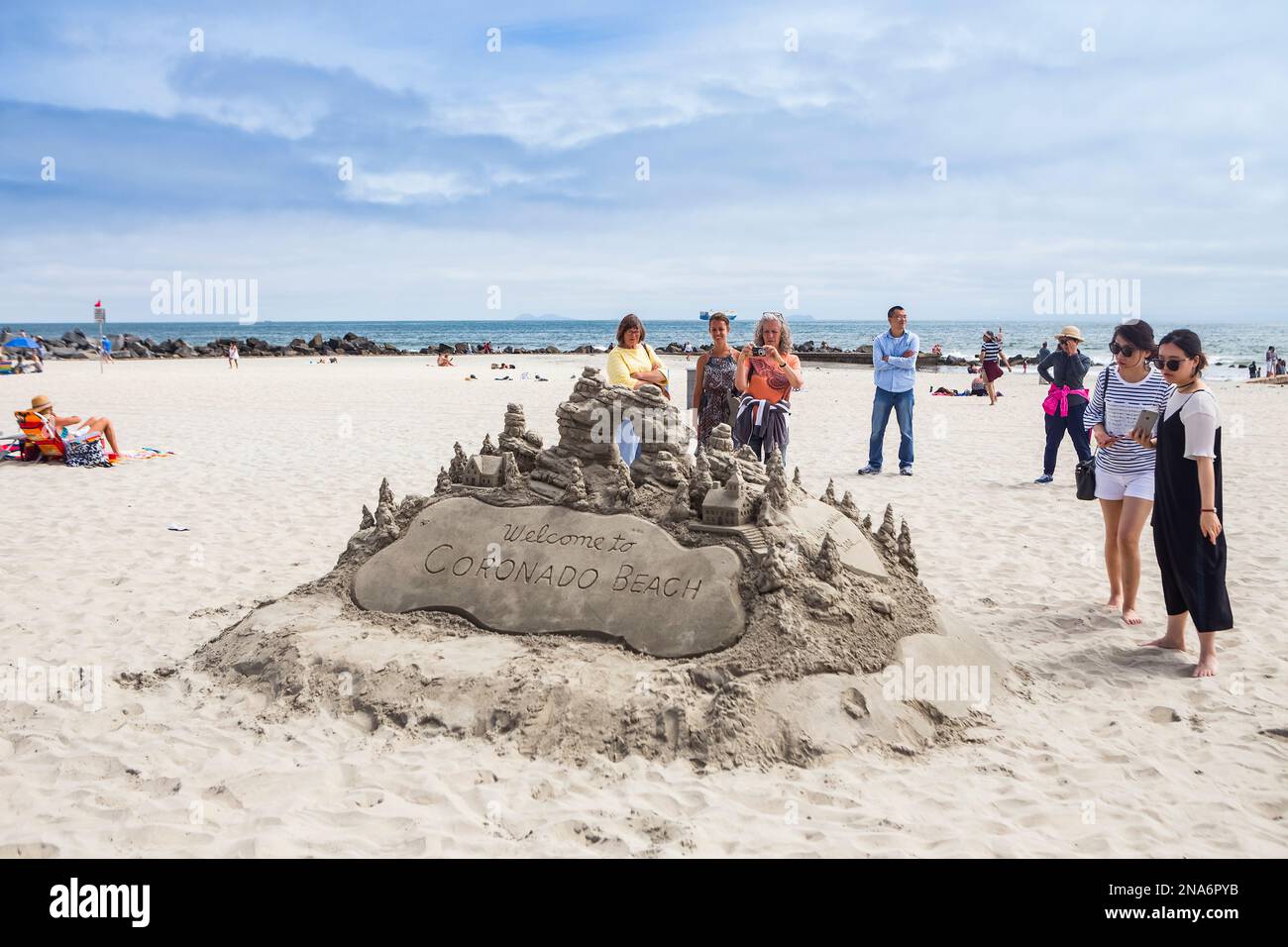Turisti che guardano un castello di sabbia sulla spiaggia di Coronado; Coronado, California, Stati Uniti d'America Foto Stock