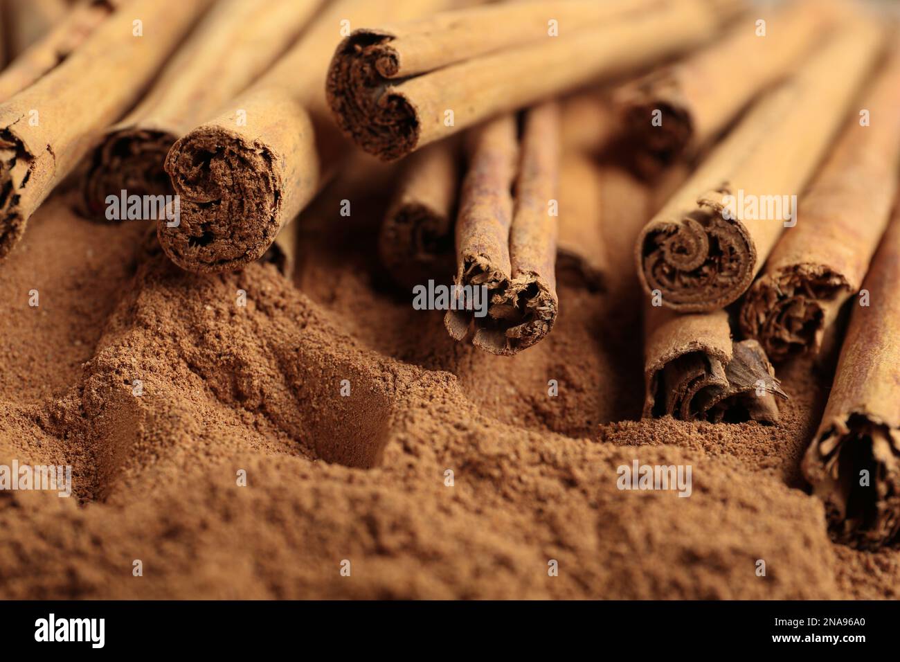 Bastoncini di cannella aromatici su polvere, vista primo piano Foto Stock