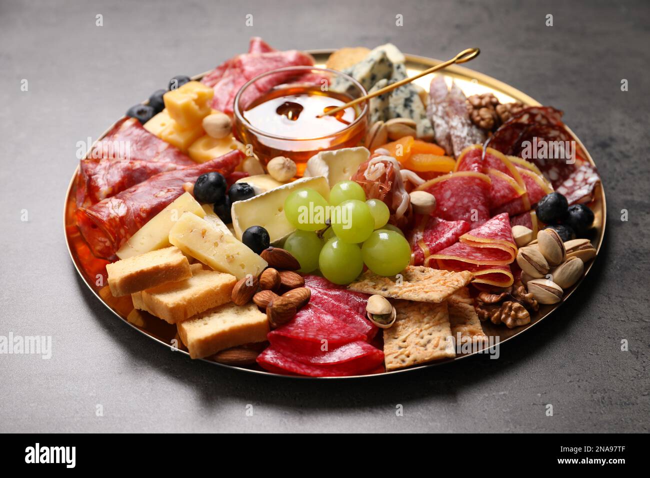 Piatto di antipasti diversi con miele su tavolo grigio, primo piano Foto Stock