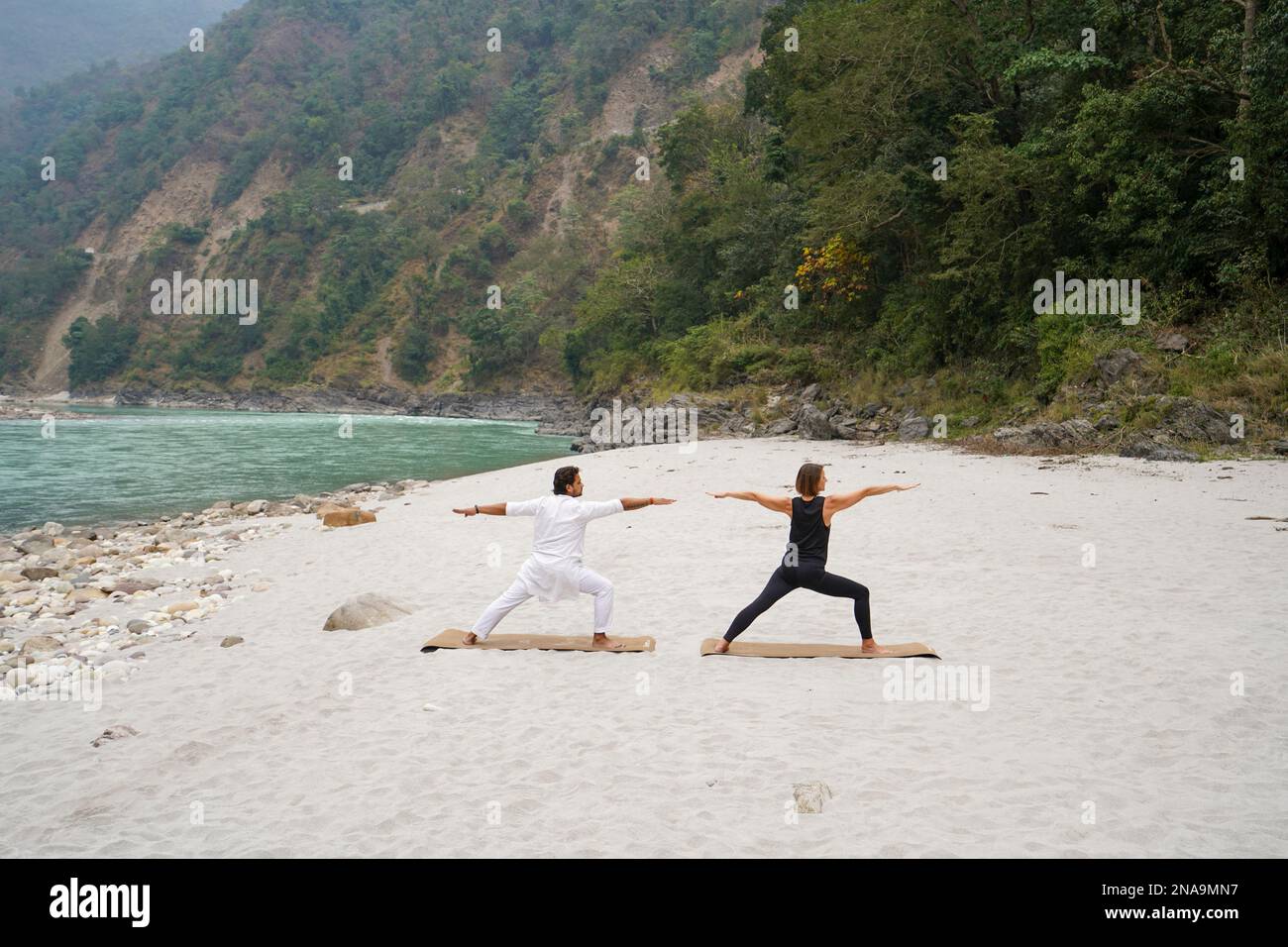 Lezione di yoga sulla riva del fiume Gange che scorre attraverso le colline pedemontane dell'Himalaya tra il Rishikesh e Devprayag nella Valle del Gange, U Foto Stock