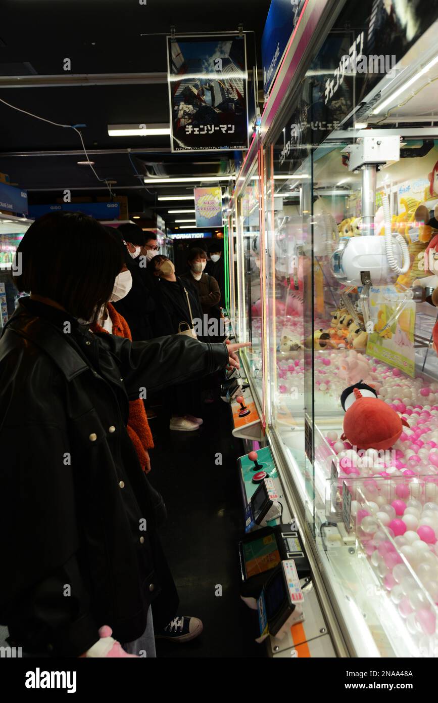 Adolescenti giapponesi che cercano di selezionare giocattoli in una gru giocattolo macchina artiglio a Tokyo, Giappone. Foto Stock