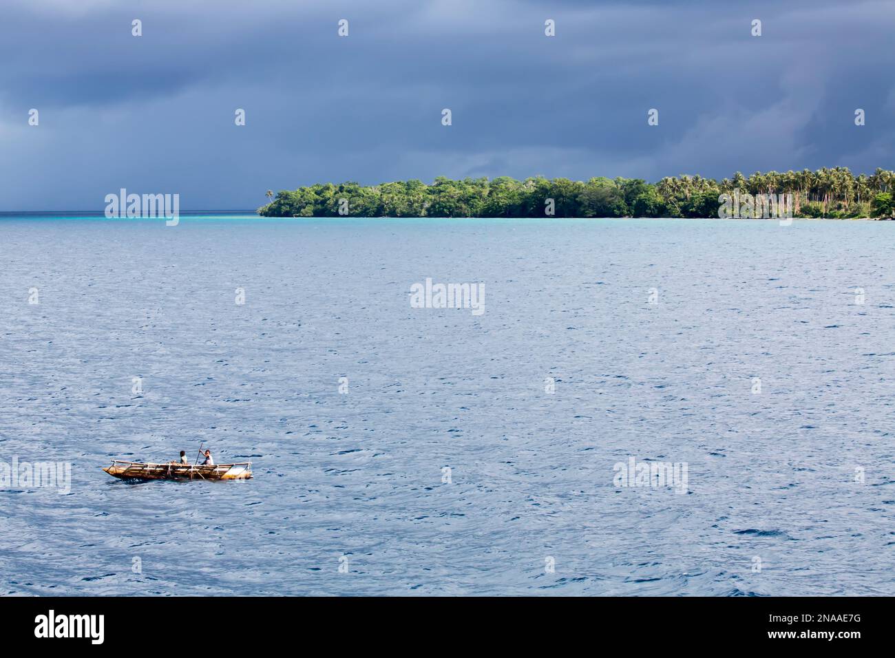 Outrigger canoa sotto il cielo tempestoso al largo della costa dell'isola di Kuiawa nelle isole Trobriand, Papua Nuova Guinea Foto Stock