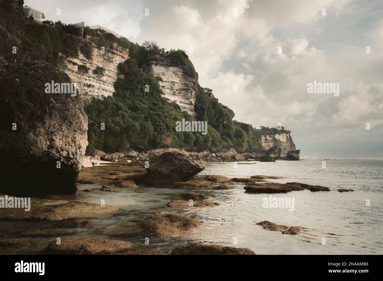 Scogliere aspre e fogliame lungo una costa con formazioni di nuvole nel cielo, Diamond Beach; Nusa Penida, Bali, Indonesia Foto Stock