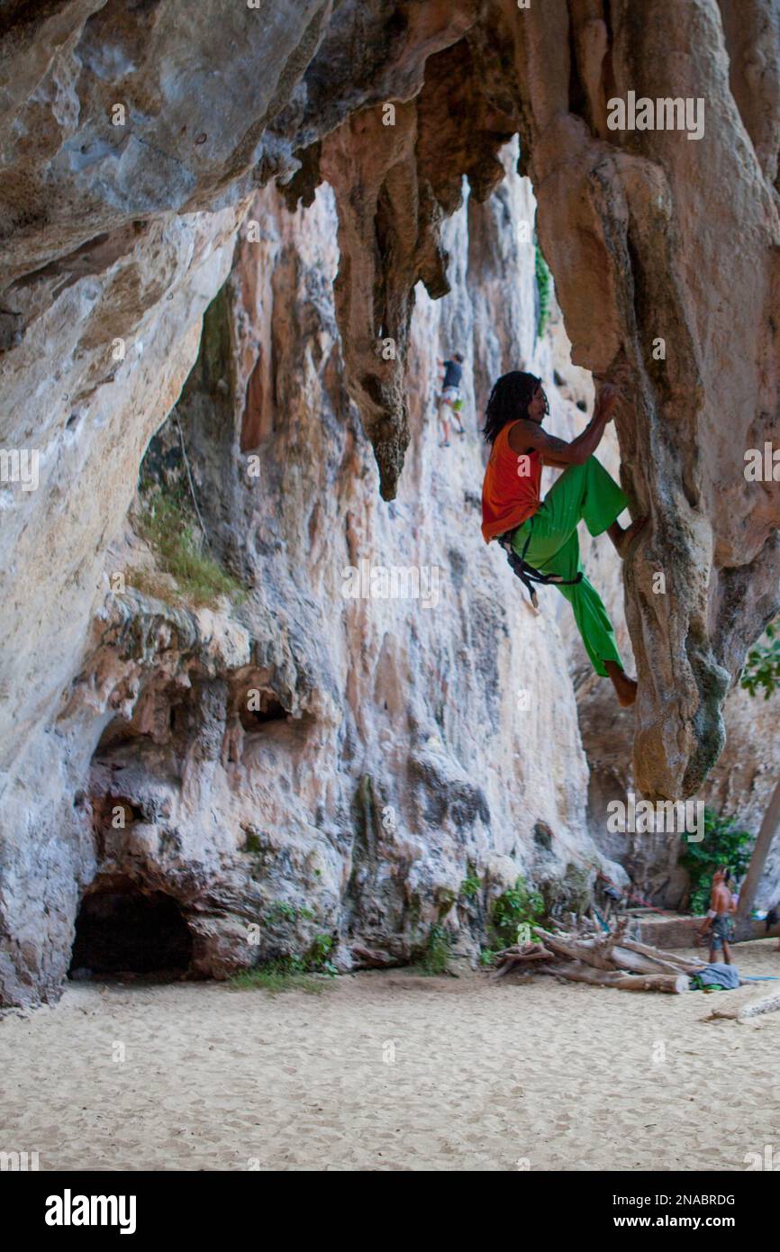 Un Thai rocciatore si arrampica la stalagtites su Koh Phangan beach. Foto Stock
