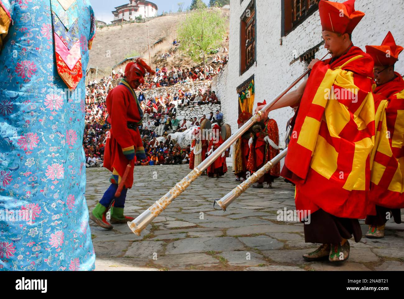 Gli artisti in costume suonano strumenti tradizionali durante una danza Cham al Festival bhutanese Paro Tshechu all'interno di Paro Dzong, un monastero e... Foto Stock