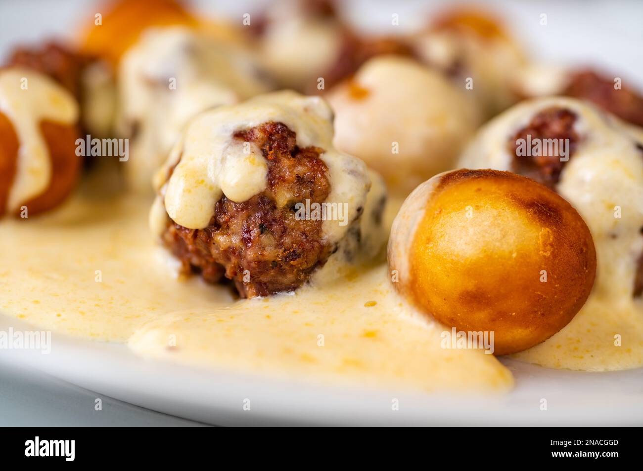 Polpetta al forno con crocchette fritte in salsa al limone al formaggio su piatto bianco, primo piano. Foto Stock