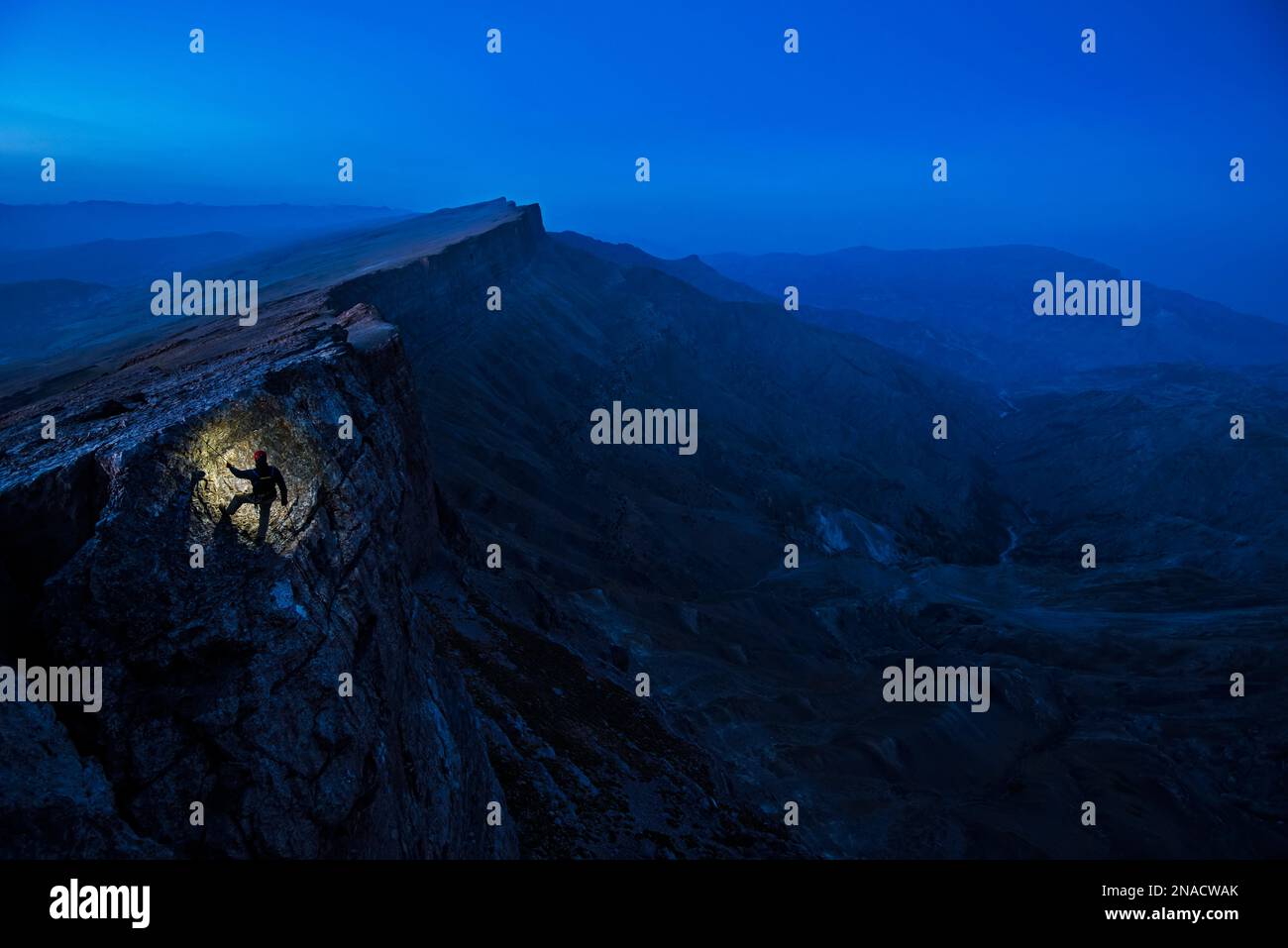 Un membro della squadra di spedizione scala una scogliera nella Boysuntov Range in Uzbekistan per esplorare Dark Star, un sistema di grotte calcaree. Foto Stock