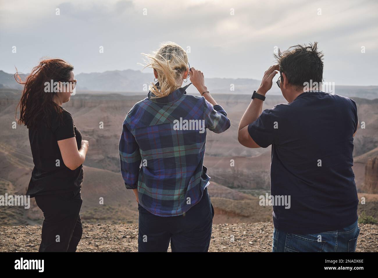 Tre persone che guardano al Grand Canyon da un punto di vista, ventoso Foto Stock