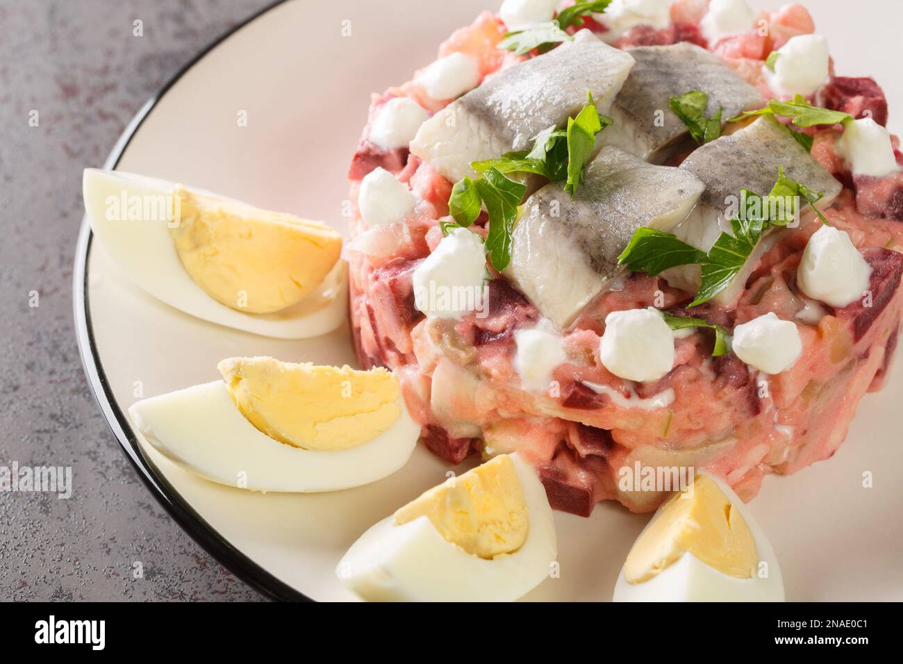 Porzione di insalata di verdure scandinave con aringhe, barbabietole, mele, patate e cipolla in un piatto sul tavolo. Orizzontale Foto Stock