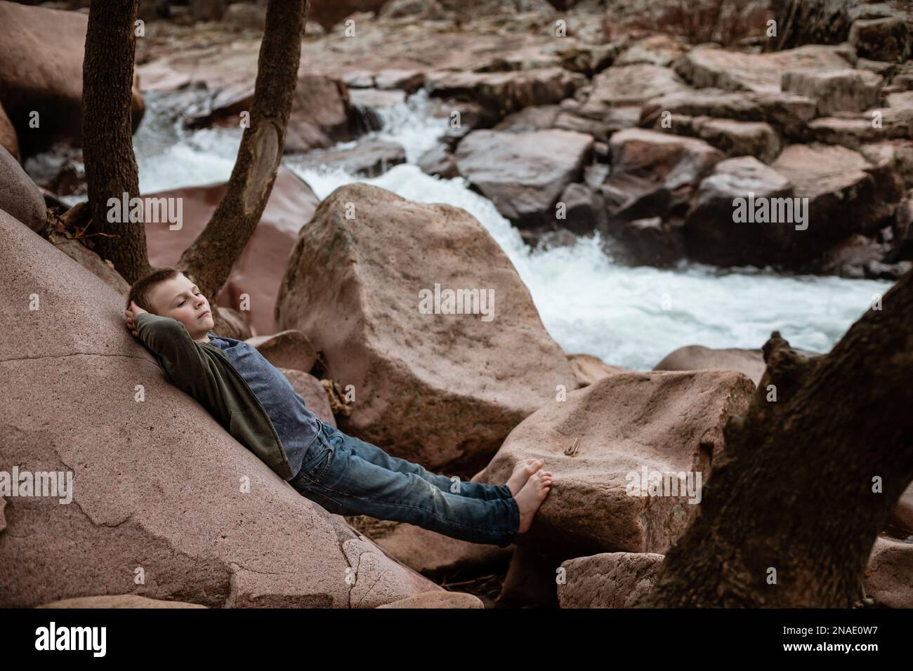 I bambini si rilassano accanto alla cascata durante un'escursione primaverile Foto Stock
