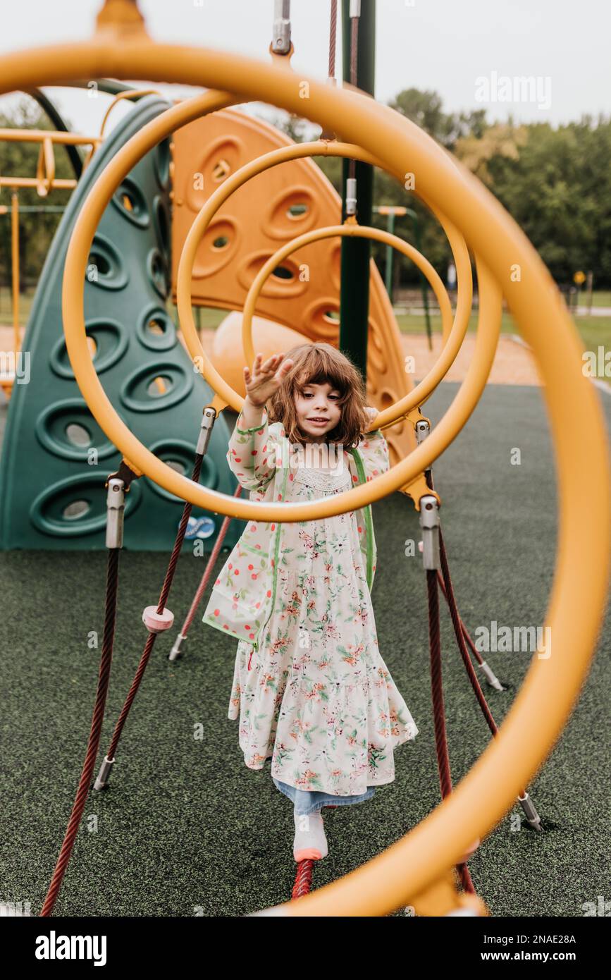 La giovane ragazza gioca sul parco giochi attrezzature nel giorno nuvoloso Foto Stock