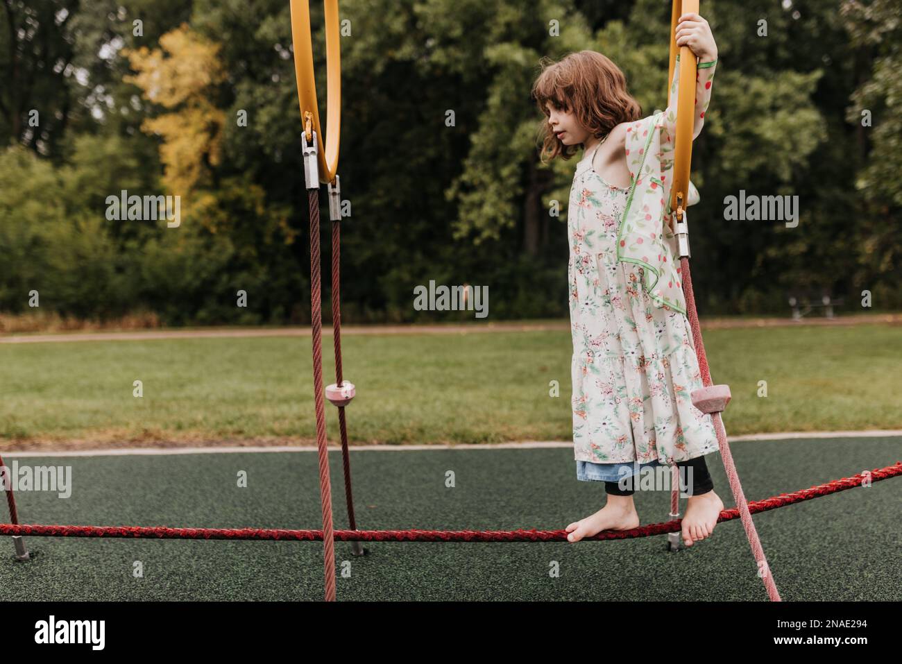 La giovane ragazza gioca sul parco giochi attrezzature nel giorno nuvoloso Foto Stock