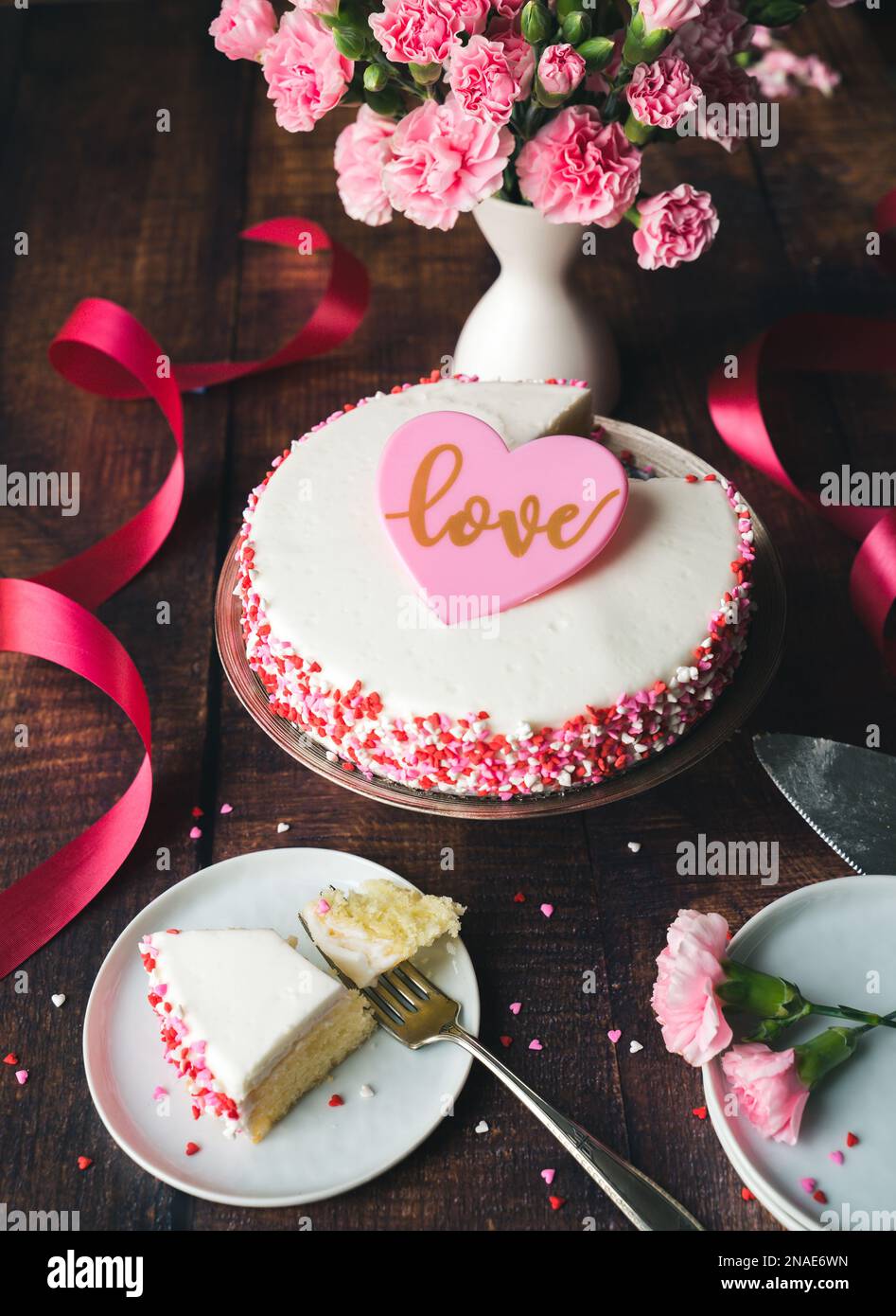 Torta di San Valentino con asperti di cuore e fiori su un tavolo di legno. Foto Stock