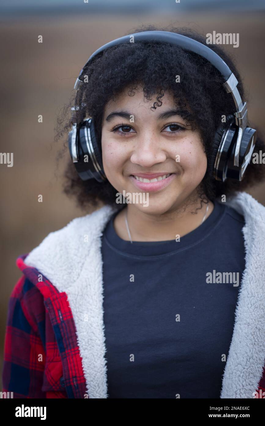 ragazza giovane biraciale che indossa cuffie e sorridente Foto Stock